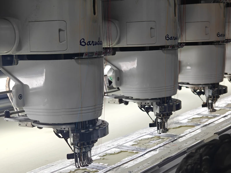 Multi-head embroidery machine needles working above flat fabric components