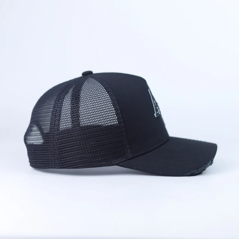 Side view of a black trucker cap with dark mesh rear panels, solid front and a distressed visor edge