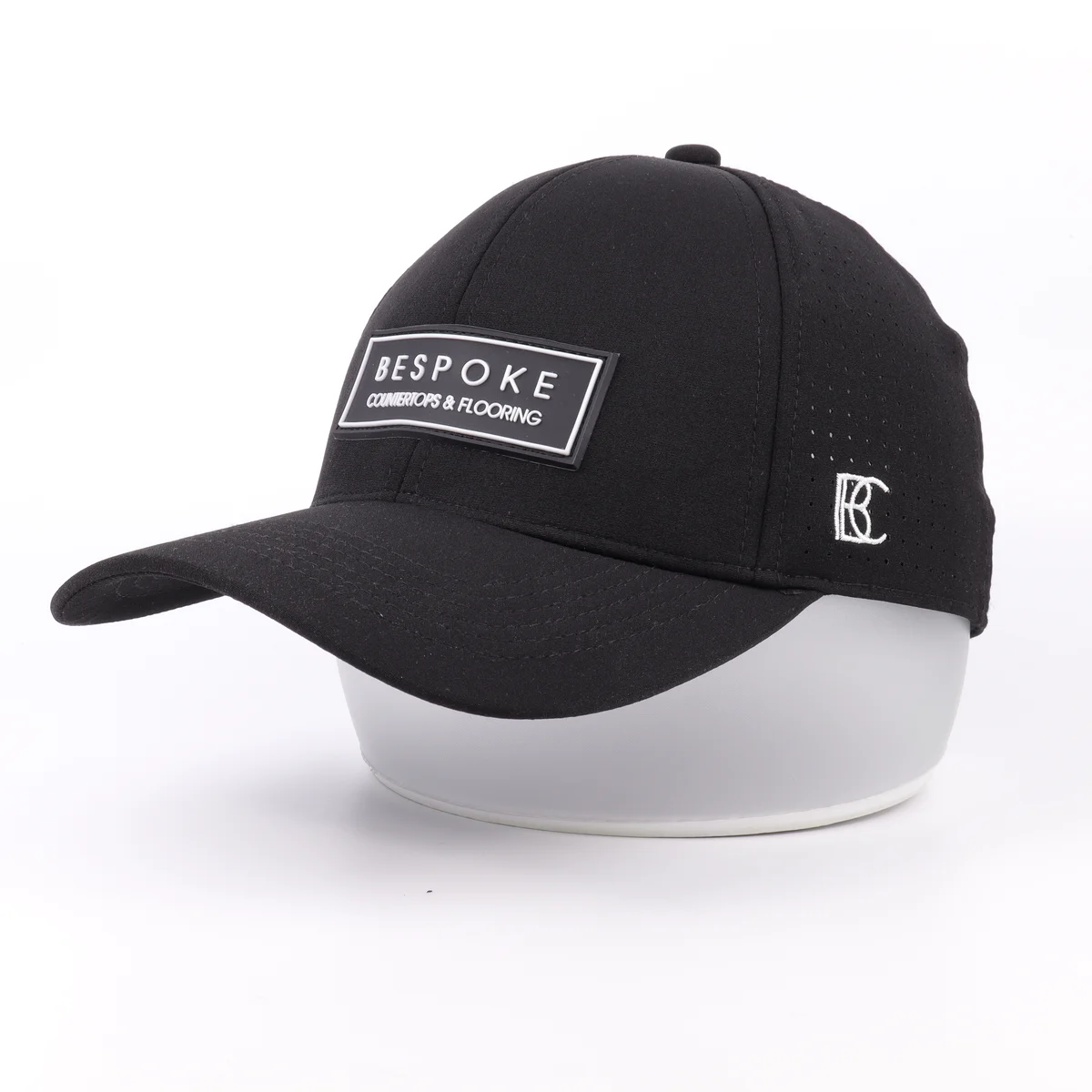 Angled view of a black patch cap showing the front panel and side embroidered mark
