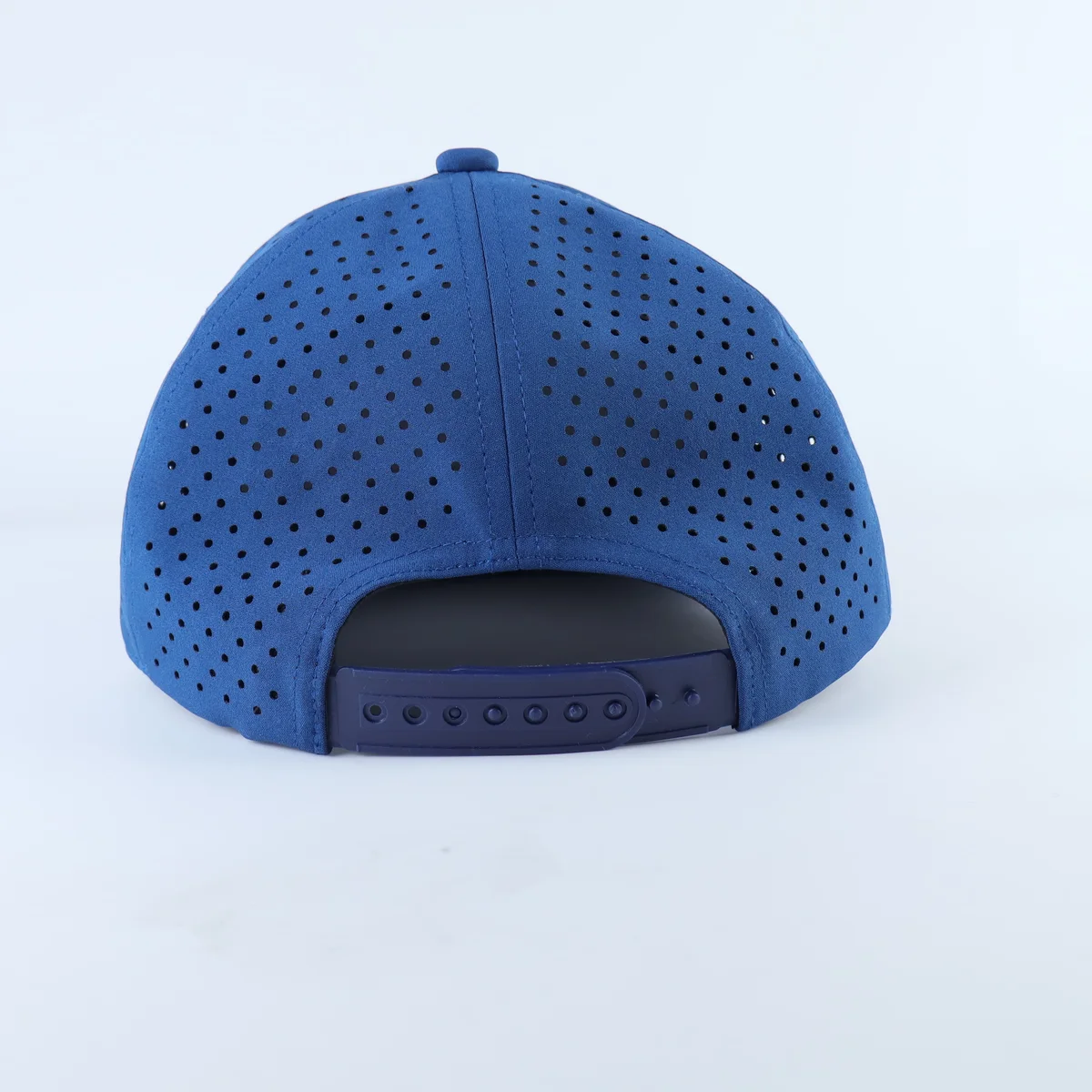 Rear of the blue perforated cap showing blue plastic snapback and crown seams