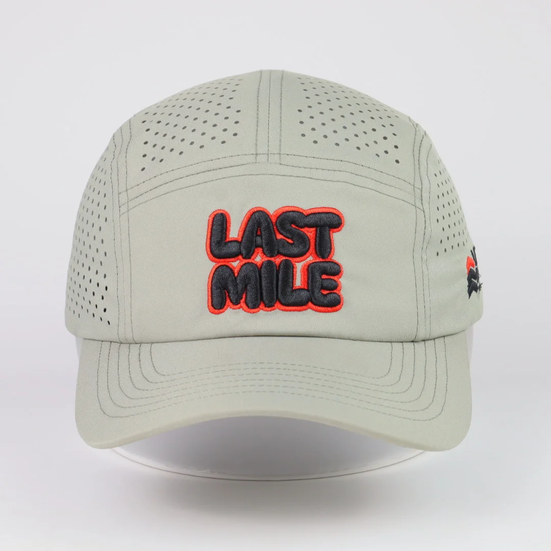 Front of sage five-panel style cap showing small embroidered lettering and perforated upper crown