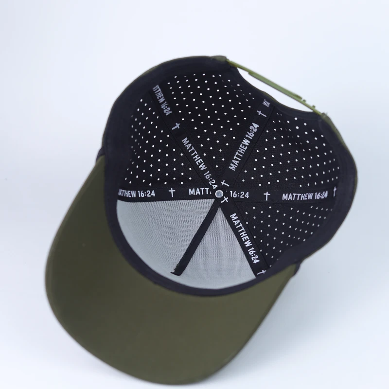 Inside of olive-green perforated cap showing printed seam tape and holes across the crown